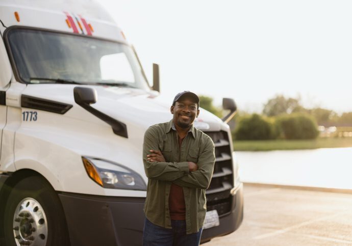 Smiling truck driver standing before white semi-truck